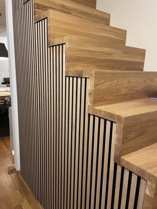 Trätrappa i hemmiljö med vertikala svarta spjälor som räcke, modern design, interiör detalj.