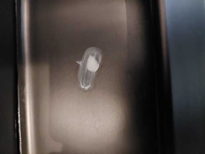 Mörk yta med vit, suddig märke eller skrapa, svagt reflekterande ljus, närbildsåtgärd.