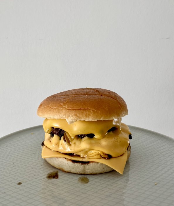 En saftig cheeseburger med smält ost och bröd på en prickig tallrik.