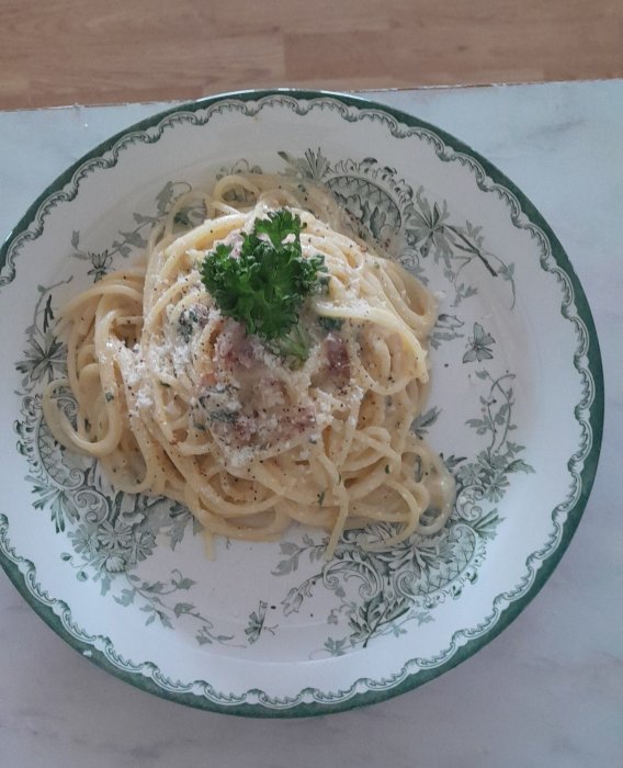 Spaghetti carbonara med persilja på dekorativ tallrik, klassisk italiensk maträtt, hemlagad.