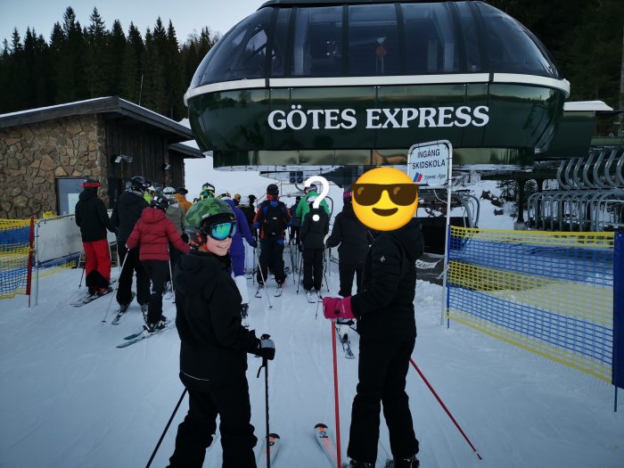 Skidåkare i kö till lift, Gôtes Express, vinterdag, skidskola skylt, snöklädda backar, skidort, utomhusaktivitet.