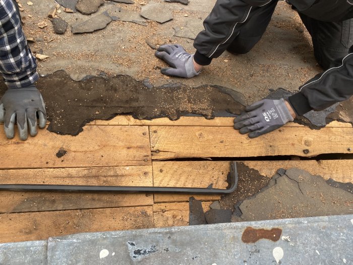 Två personer arbetar med träplankor över en spricka i golvet.