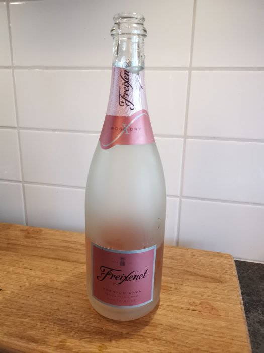 En kyld flaska Freixenet Premium Cava Rosé Dry står på ett träbord framför kakelvägg.