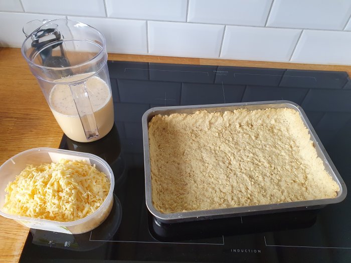 Matlagningsscenen: smoothie i mixer, riven ost, ugnsform med färdig röra.