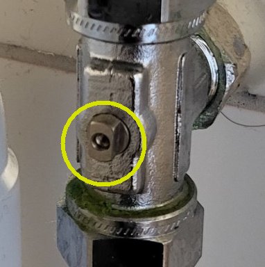 Detalj av rörkoppling med en gul markerad skruv. Metalldelar med synliga slitagespår.