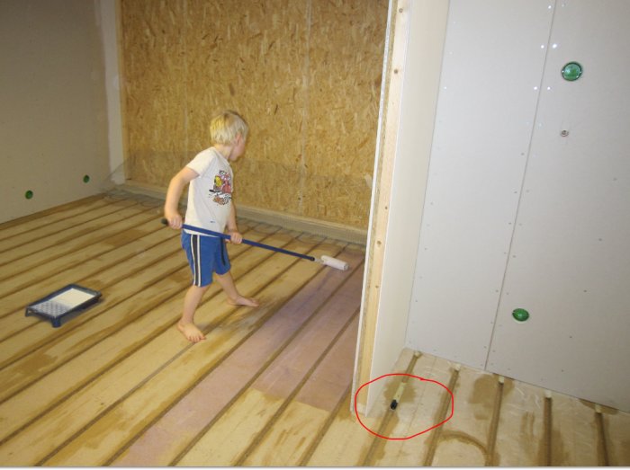 Pojke målar trägolv, vit färg, roller, barfota, inomhus, renovering, träväggar, målarbricka, röd cirkel markerar föremål.