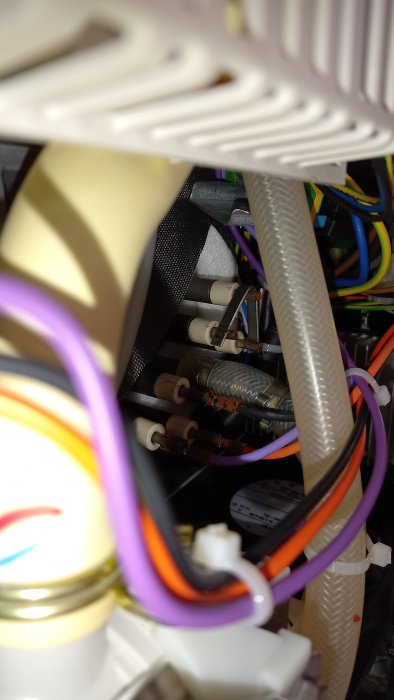 Närbild på elinstallation med kablage, möjligtvis inuti en apparat, detaljer oskarpa, fokuserade på förgrunden.