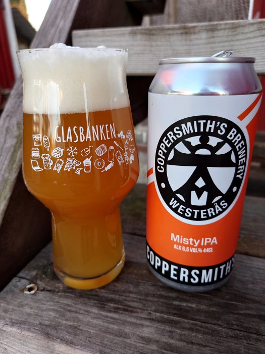 Ett glas öl märkt "GLASBANKEN", ett ölburk "Coppersmith's Brewery Westeras Misty IPA". Träbänkyta i bakgrunden.