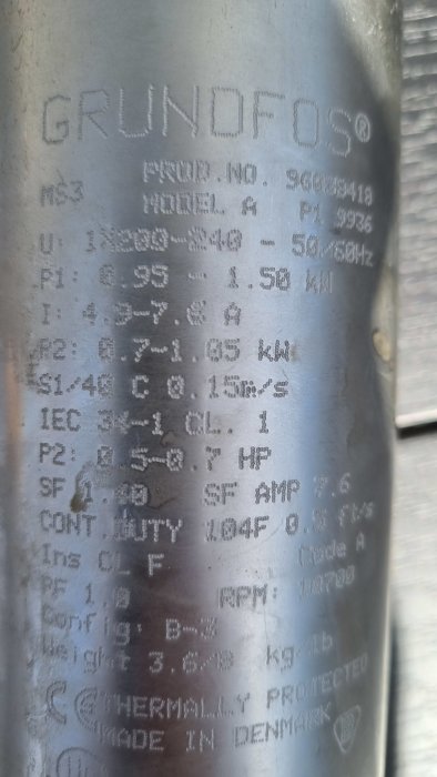 Teknisk etikett på metall med specifikationer för pump; modell, effekt, ström, frekvens, skyddsklass, tillverkad i Danmark.