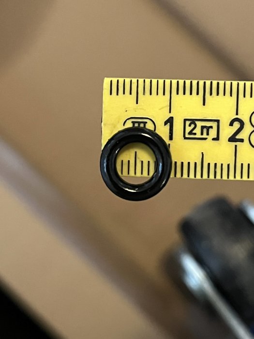 Måttband mäter objekt, cirka 12 millimeter diameter, fokus på liten cirkulär del.