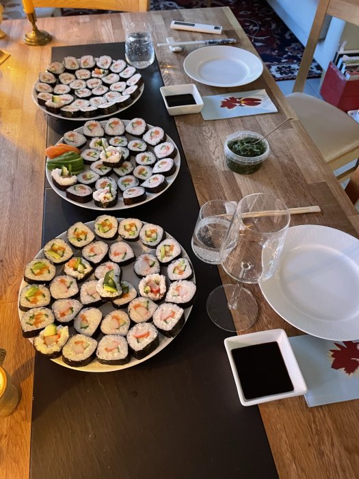 Ett bord dukat med sushi, sojasås, tomma tallrikar och glas.