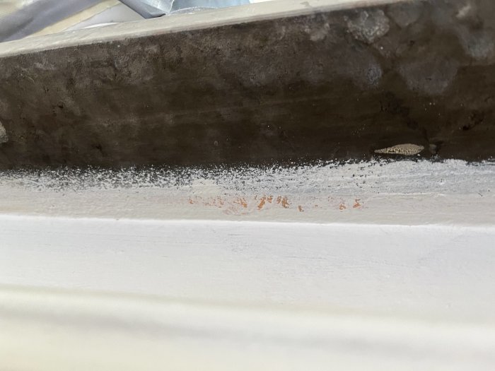 Mögelskador och fuktmärken under ett fönster; behov av underhåll eller reparation.