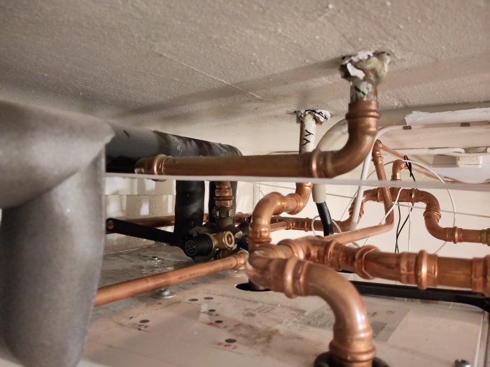 Rörsystem med kopparledningar och isolering under vitmålat tak, teknisk installation.