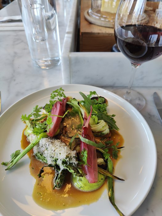 Gourmetmat på tallrik, rödvin, elegant restaurangmiljö, fint dukat bord.