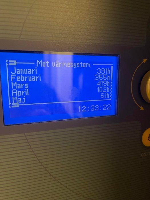 LCD-skärm visar drifttider för värmesystem per månad, klockslag nedtill.