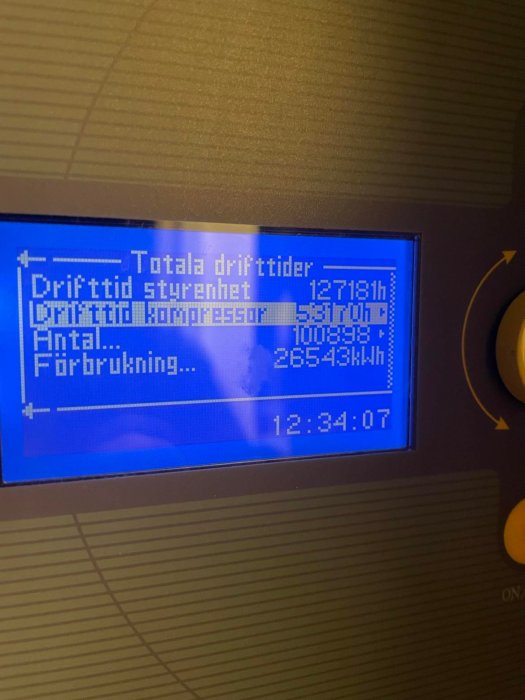 Digital display visar drifttider och energiförbrukning på svenska, möjligen för värmepump eller liknande system.