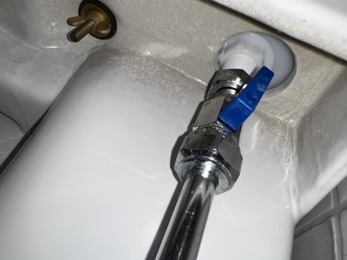 Tvättställ med vatten, silverfärgad vattenlås, blå isolerband, vit PVC-rör, brun kran i bakgrunden.