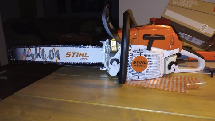 Motorsåg av märket STIHL MS 261 C ligger på ett träbord, ny eller väl underhållen.