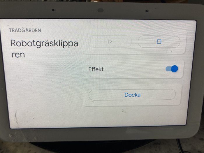 En skärm som visar gränssnitt för en robotgräsklippare med alternativ för effekt och dockning.