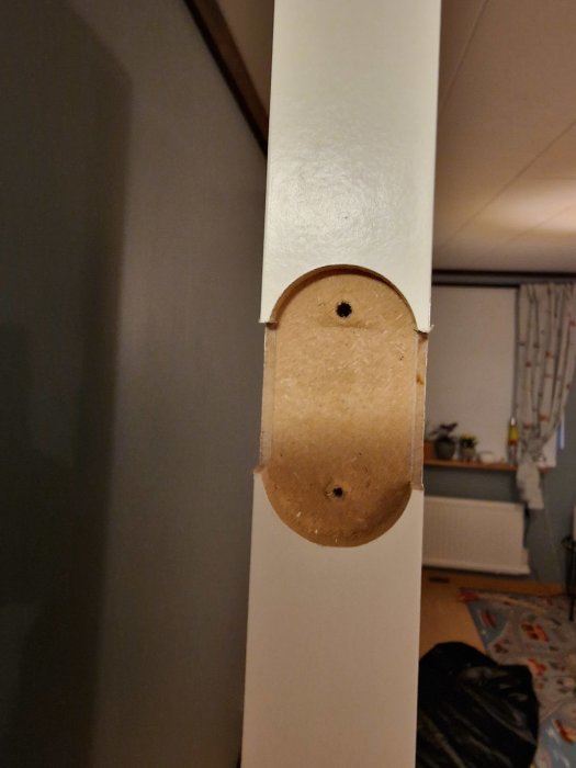 Rund träbit på vit pelare, inomhus, avskalad yta, obearbetad träyta, rum bakgrund, vardagsmiljö.