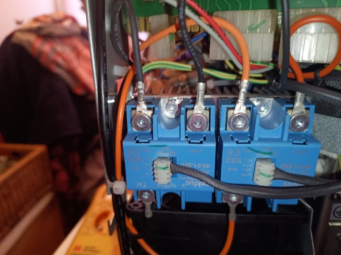 Elektrisk anslutning, terminalblock, kabelanslutningar, säkringshållare, blå och grå komponenter, otydlig omgivning.