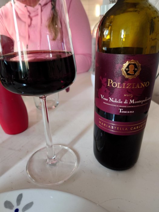 Ett glas rödvin och en flaska Vino Nobile di Montepulciano, Poliziano, årgång 2019 från Toscana, Italien.