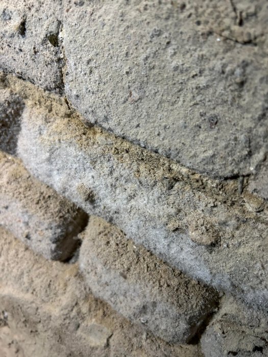 Närbild på en grov yta, möjligen betong eller sten, med ojämna linjer och grå nyanser.