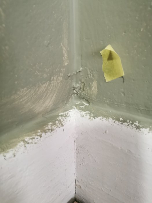 Vägghörn med avskalad färg, fuktskada och en gul post-it-lapp.