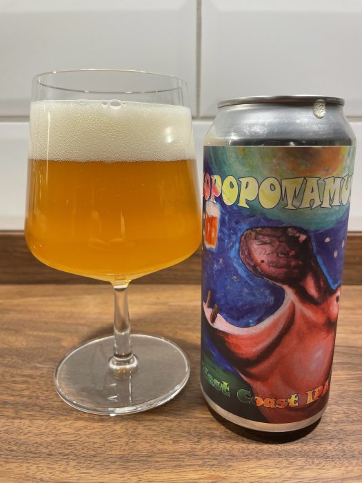 Ölglas med skummad dryck, färgglad burk med hippon, text "West Coast IPA".