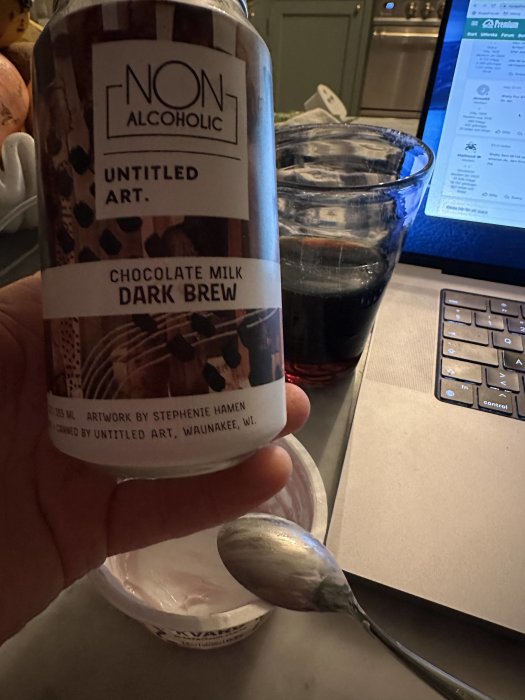Burk med alkoholfri chokladmjölksdryck, laptop i bakgrunden, tom skål, sked.