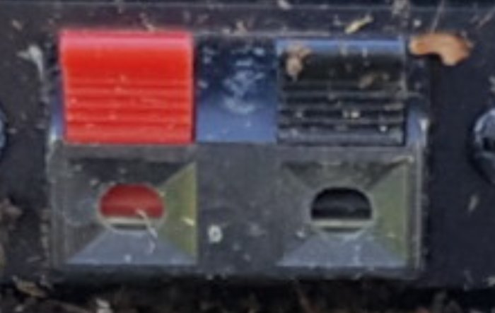 Sliten kontrollpanel med knappar, röd varningsetikett, smutsig, skadad yta, otydliga symboler, möjlig industriell utrustning.