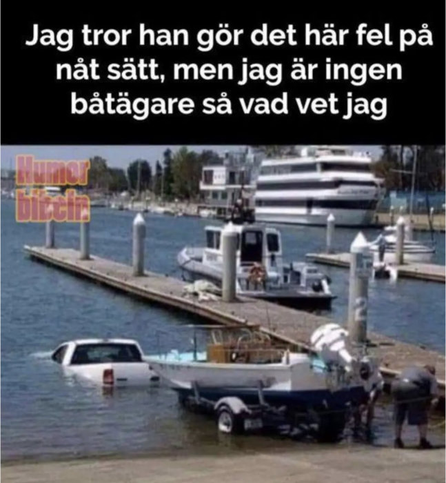 Bil halvvägs nedsänkt i vattnet vid brygga, troligt fel vid båtupptagning, humoristisk text ovanför.