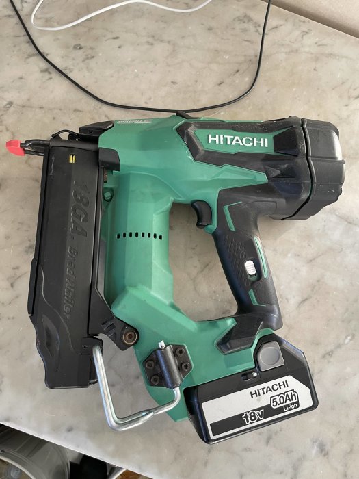 Hitachi batteridriven spikpistol på marmorbänk, 18V, 5.0Ah Li-ion, säkerhetsspärr synlig.