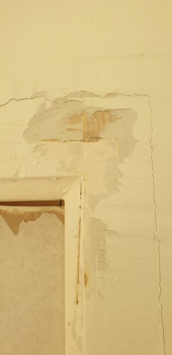 Skadad vägg med flagnande färg och tapet vid hörn, behov av renovering eller reparation.