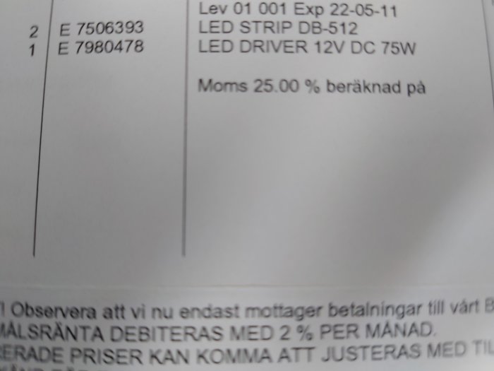 Ett suddigt foto av ett dokument med artikelnummer, produktnamn, och text om moms och betalningsinformation på svenska.