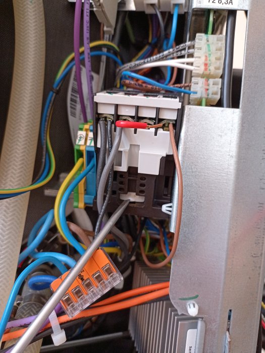 Ett elskåp med många färgkodade kablar, anslutningar och komponenter, indikerar en elektrisk installation.