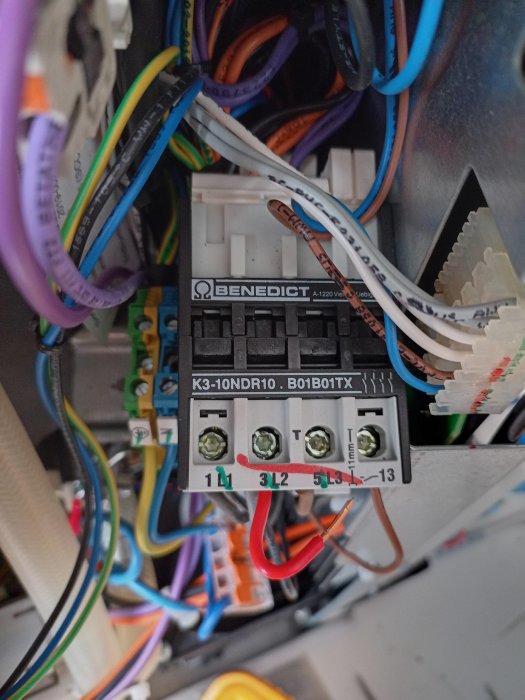 Elektrisk kontaktor med anslutna färgade ledningar i en elektrisk tavla; industriell eller kommersiell miljö.