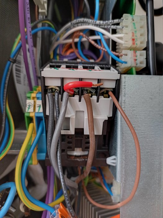 Elektrisk komponent med färgkodade kablar och kontakter. Möjlig säkerhetsrisk synlig.