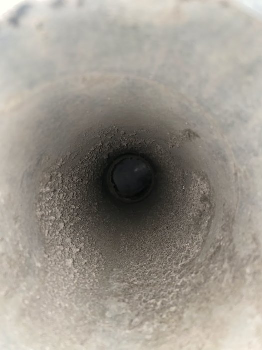 Ett objekt ser ut som en mörk sfär i änden av en grå tunnel.