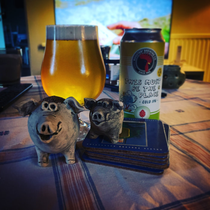 Ett ölglas, burk, små grishantverk och plånbok på ett bord inomhus.