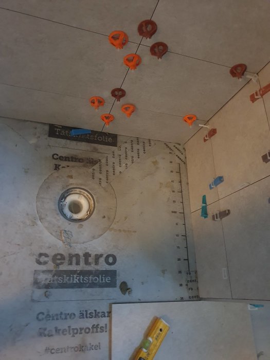 Inre tak med orange pluggar, kablar, isolering, byggmaterial, och ett måttband på en sliten yta.