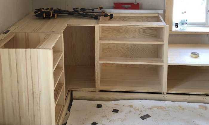 Träsnickeri, omonterade köksskåp, verktyg, pågående arbete, inomhus, byggnadsprocess.