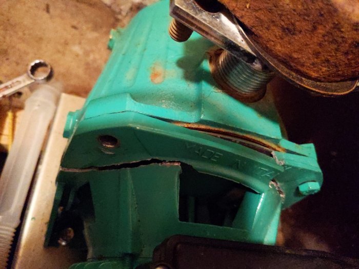 Turkos växelhus, rostig fjäder, verktyg, mekaniska delar, minstyrka utsliten, sladd, mörk bakgrund, närbild.