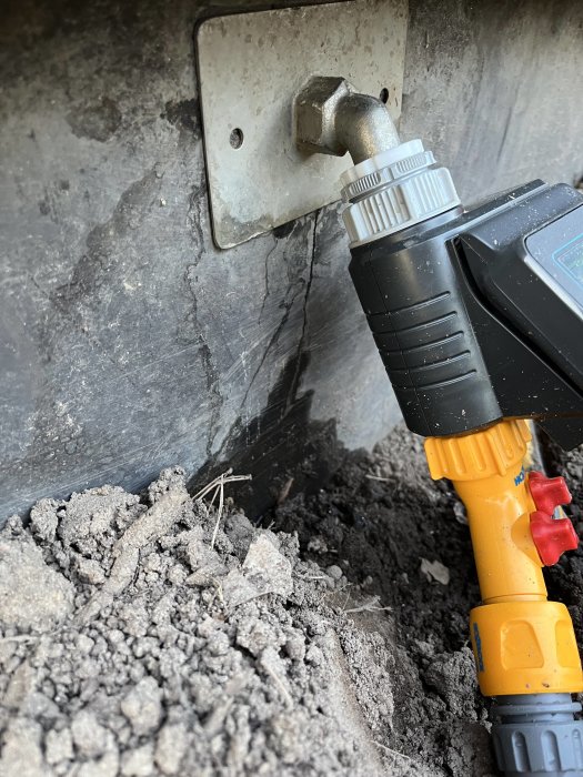 Elverktyg anslutet till en röranslutning bland grus och smuts.