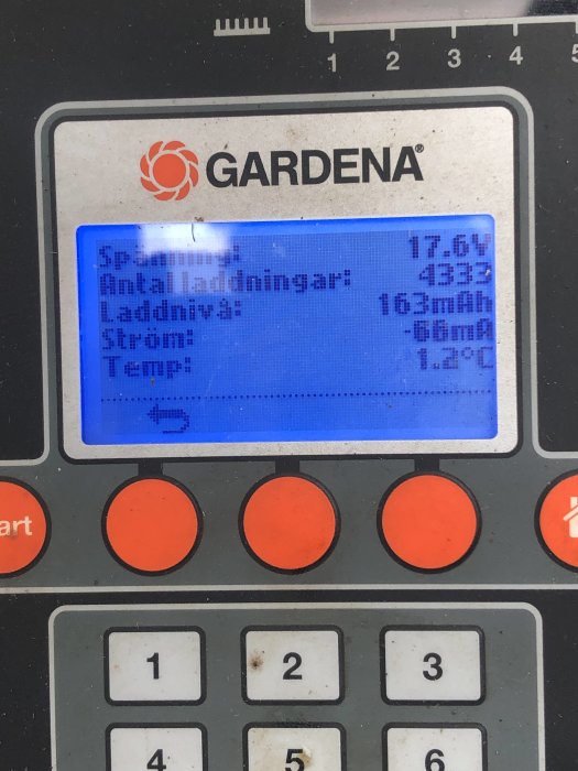 Gardena-batteriladdare med LCD-skärm visar spänning, laddningstid och temperatur; knappar nedanför skärmen.