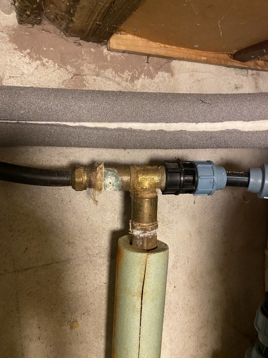 VVS-installation med isolerade rör, ventiler och anslutningar i ett källarutrymme.