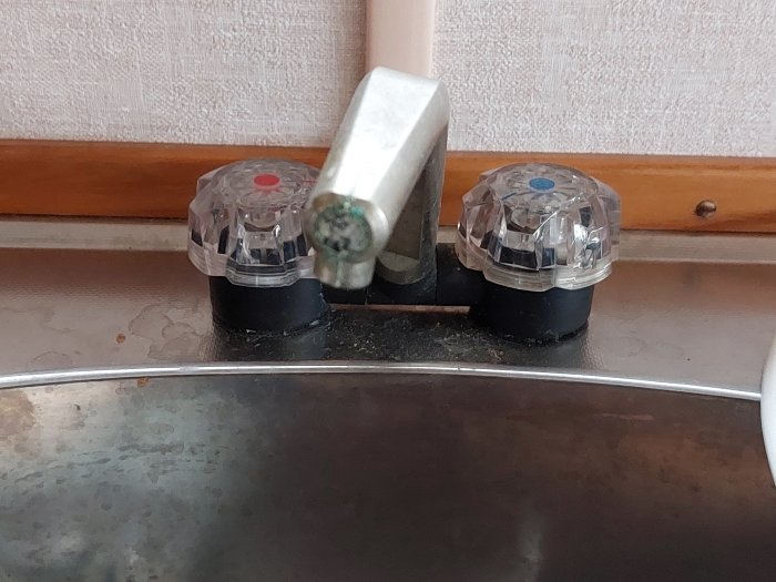 Duschblandare med röd och blå markering, metall, slitage, köksfläkt reflektion, kakel, träkant.