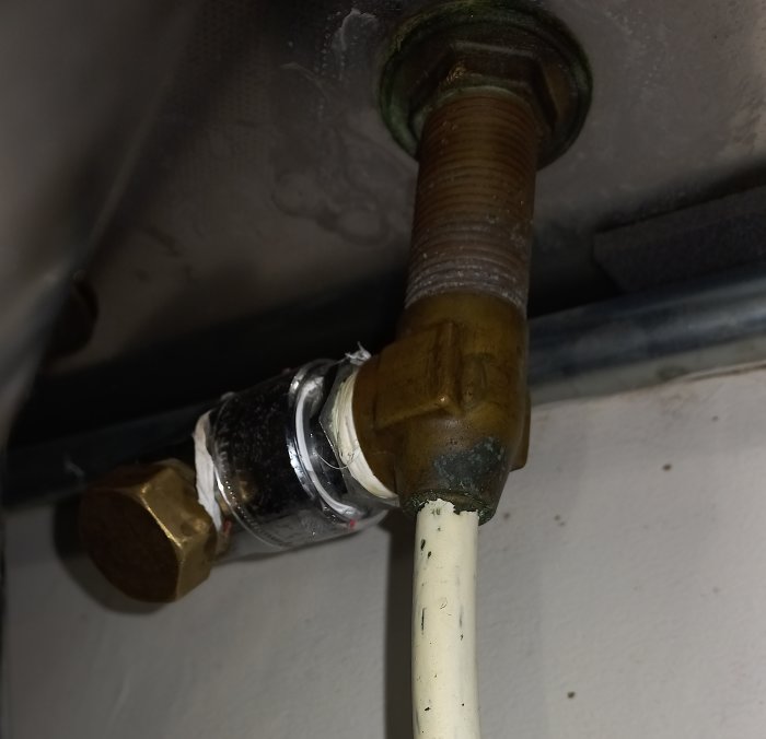 VVS-installation med kopplad rörledning och ventil, synlig isolertejp och korrosion, i ett underhållsbehovande skick.