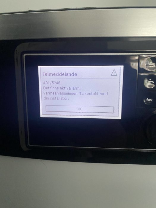 Skärm på värmesystem visar felmeddelande med kod, instruerar kontakt med installatör.