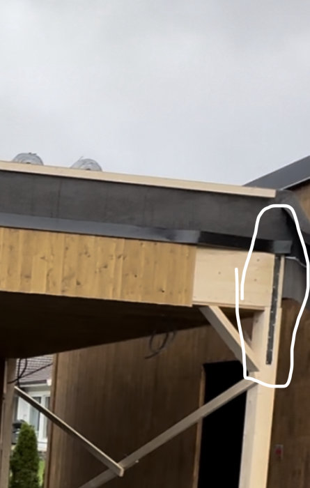 Del av en träkonstruktion, sannolikt en byggnad, under uppbyggnad med synliga reglar och stödben.
